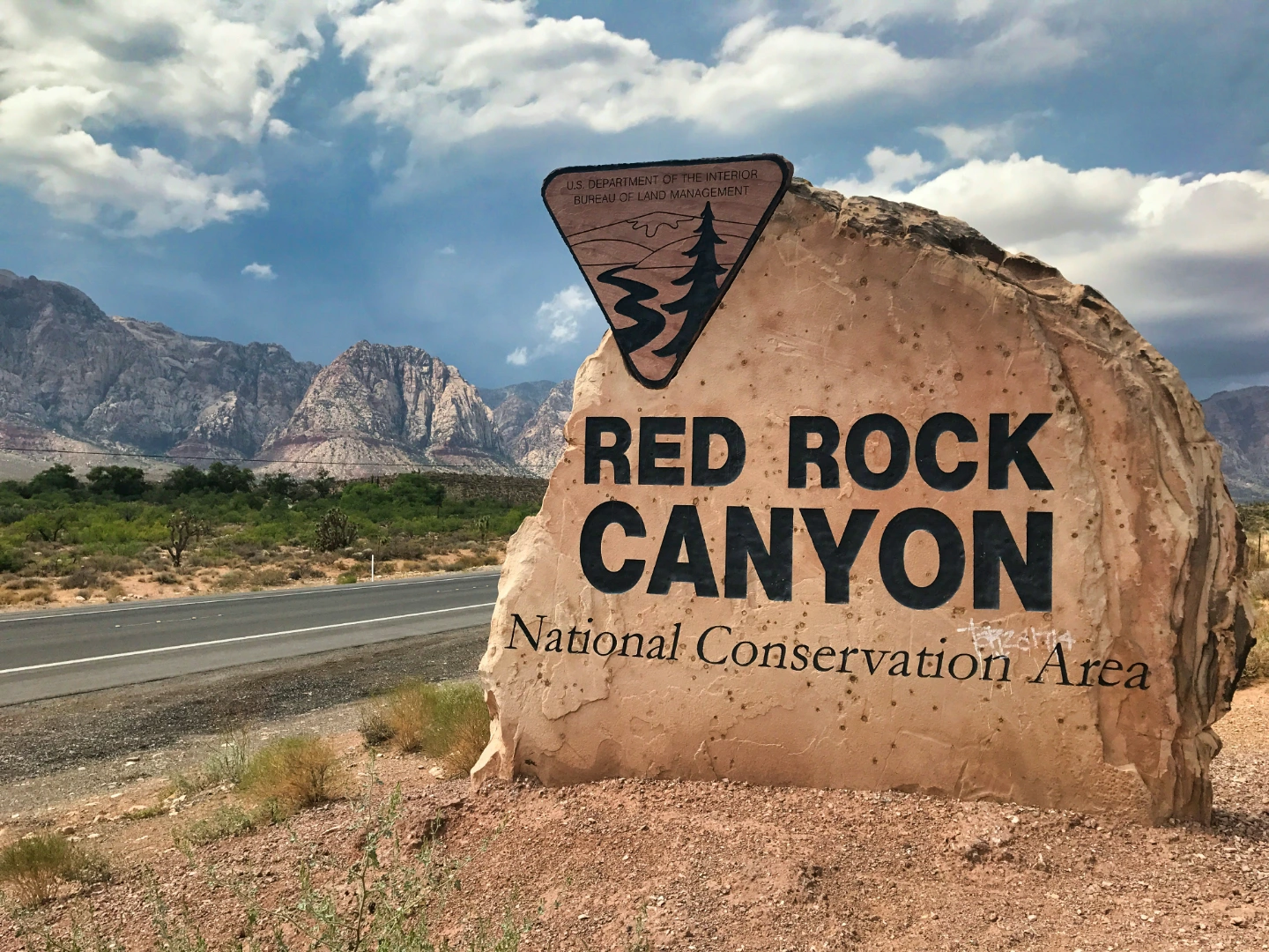 Red Rock Canyon National Conservation Area entrance sign beside a desert road