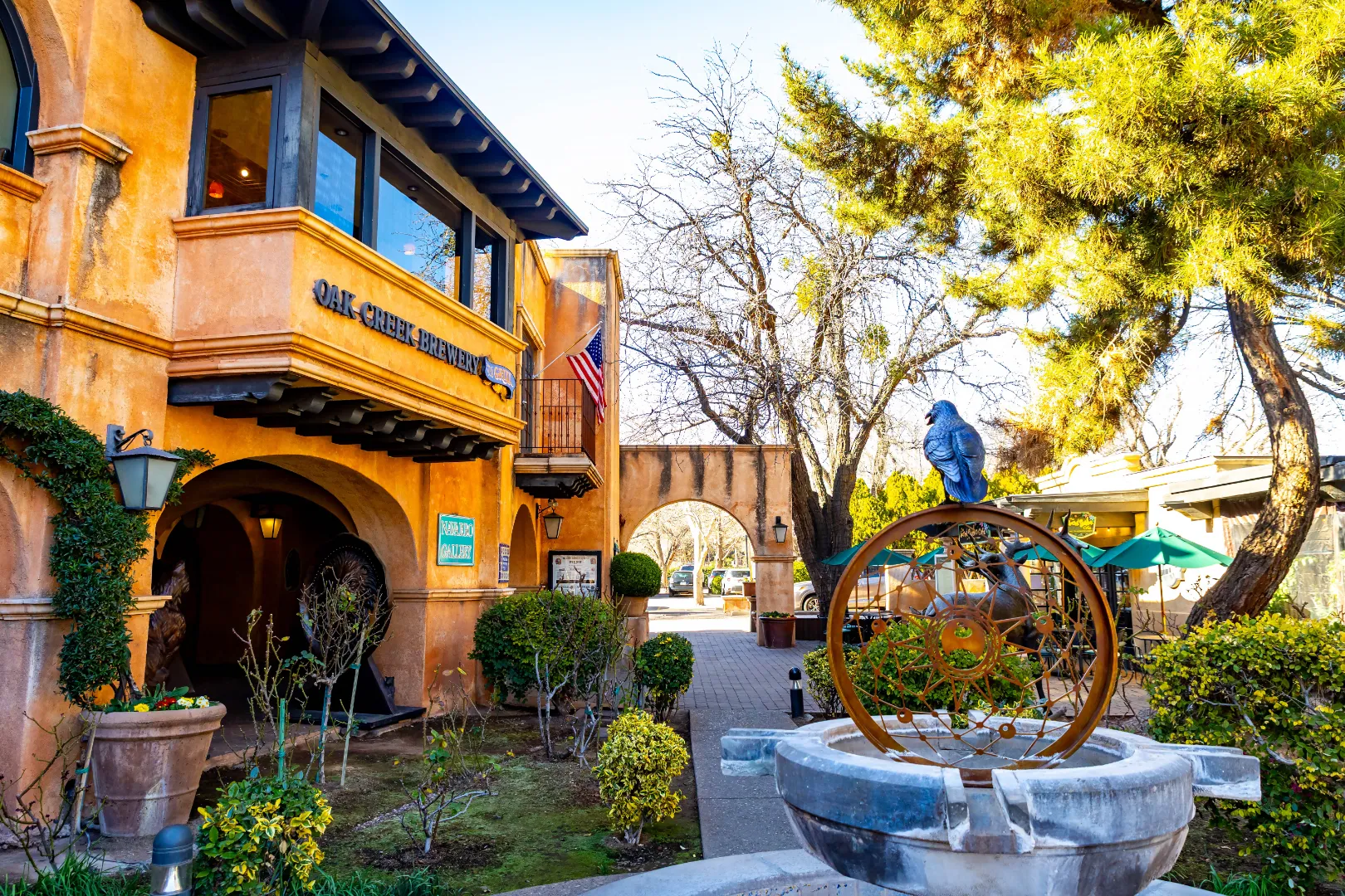 Tlaquepaque courtyard with a stone fountain, Spanish-style buildings and sunlit trees