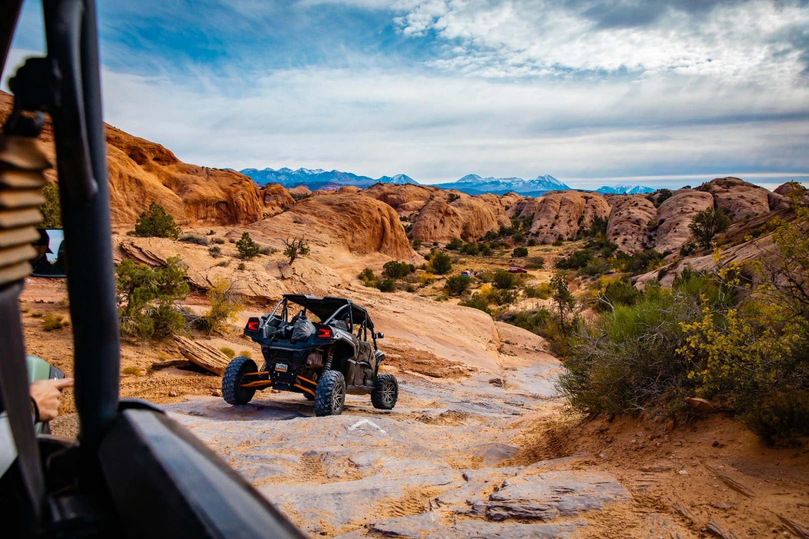 Off-road vehicle parked on slickrock with red rock formations, typical of a Sedona jeep tour