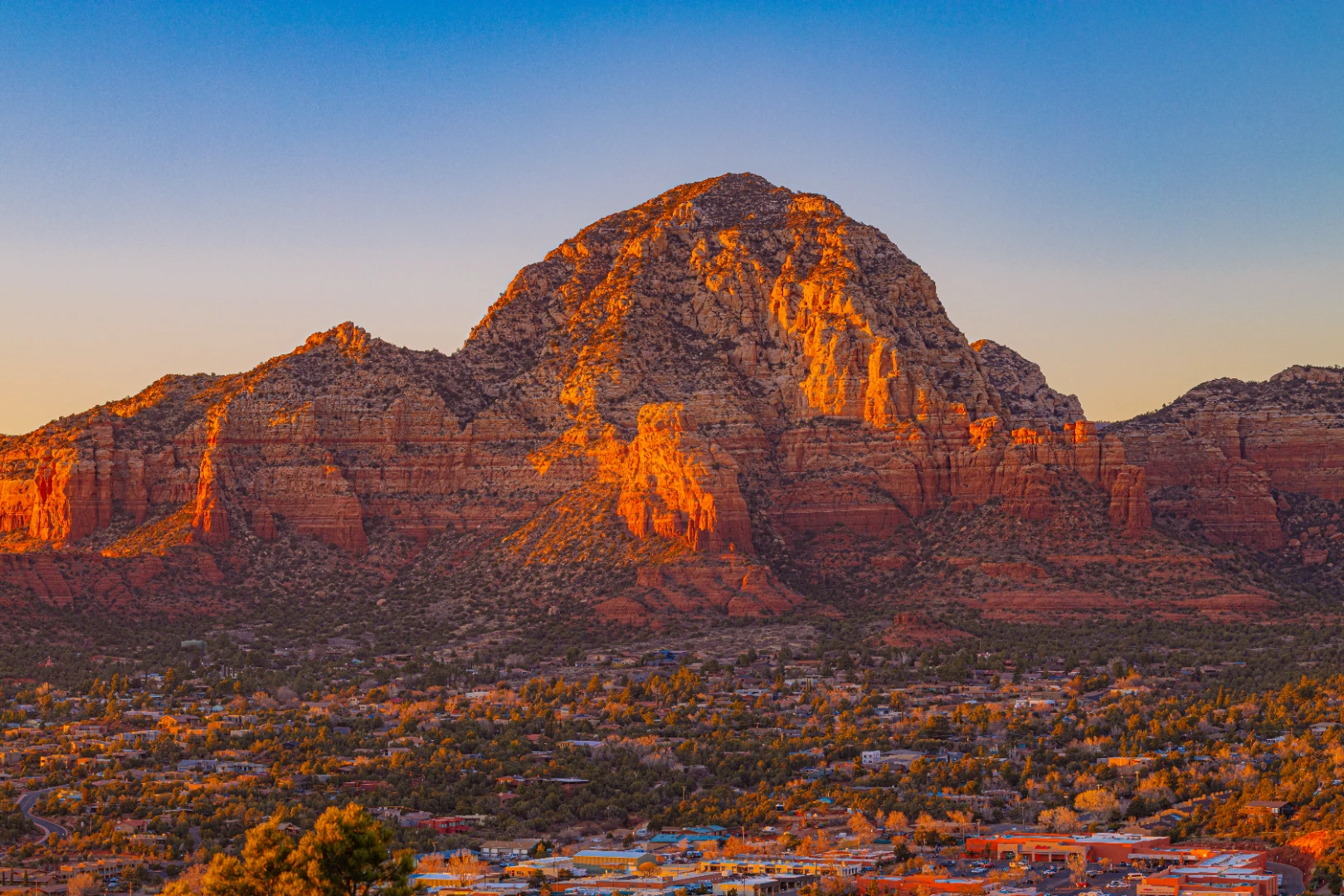 Capitol Butte glowing orange at sunset above the town of Sedona