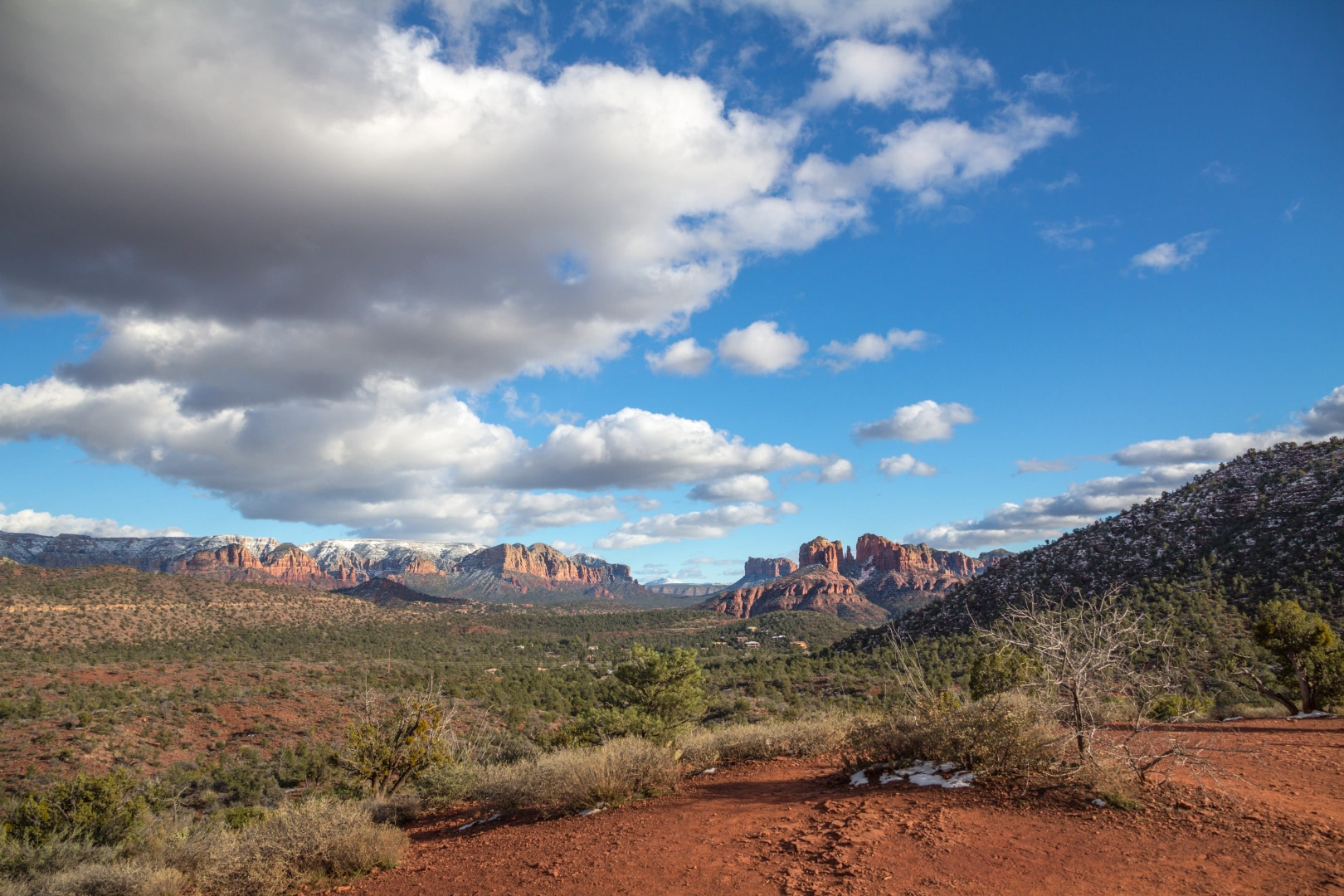 Wide Arizona desert landscape with distant red rocks under a bright, cloudy sky