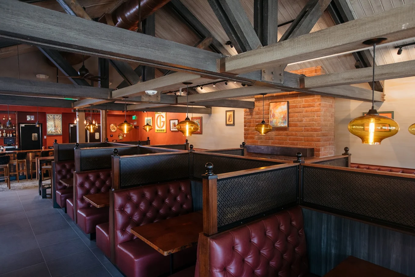 Cozy dining room with tufted red leather booths, exposed beams and warm pendant lights