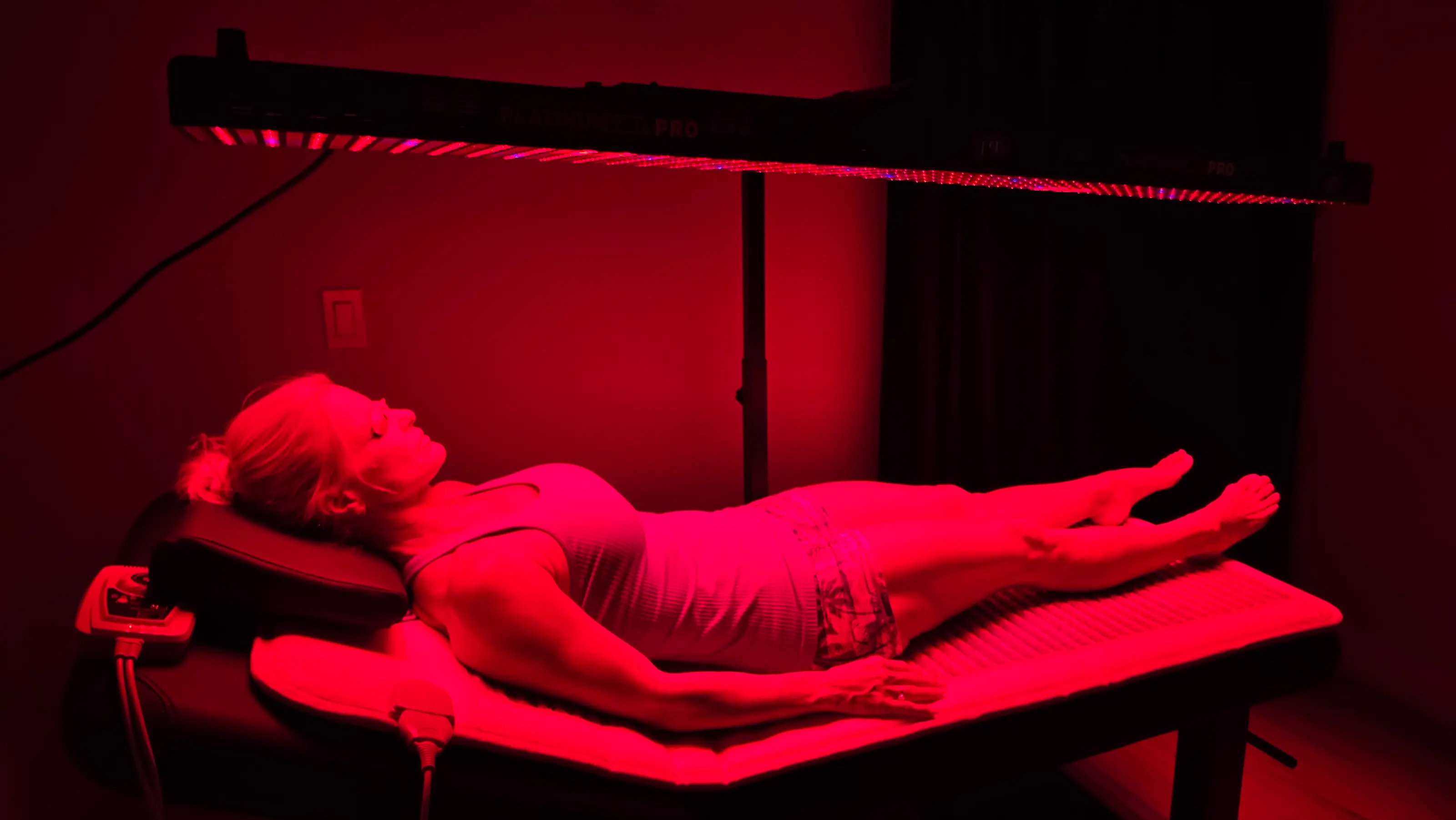 Red light panel glowing along its underside above a guest resting on the mat in the Arroyo Pinion red light room