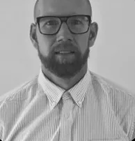 Black-and-white portrait photo of a man wearing glasses and a striped shirt