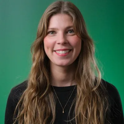 Portrait photo of a smiling woman with long brown hair against a green background