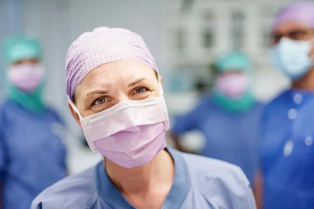 Healthcare worker in scrubs and a surgical mask in a clinical setting