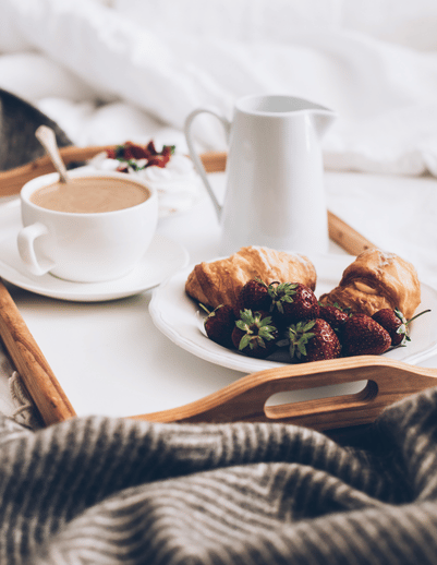 Coffee and pastries on a breakfast tray in bed