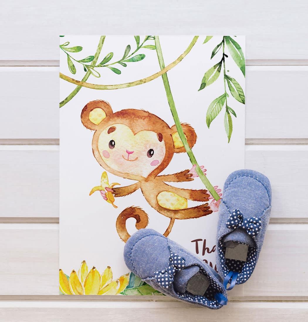 A monkey thank you card next to a pair of blue baby shoes