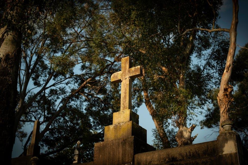 A stone cross among tall trees against the sky