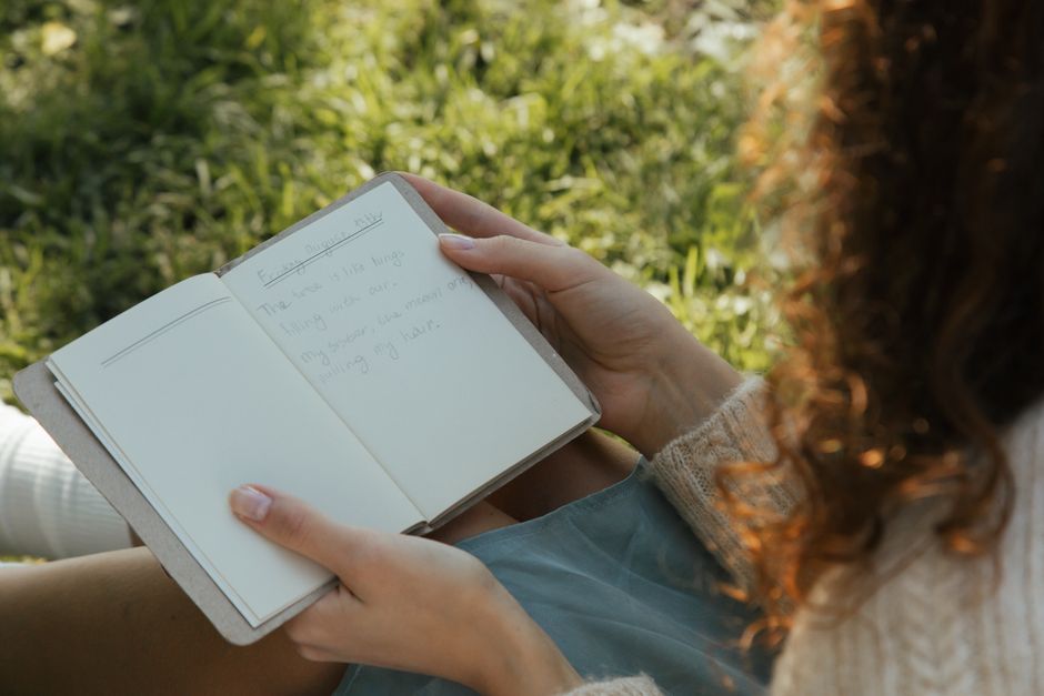 Person reading a handwritten notebook outdoors