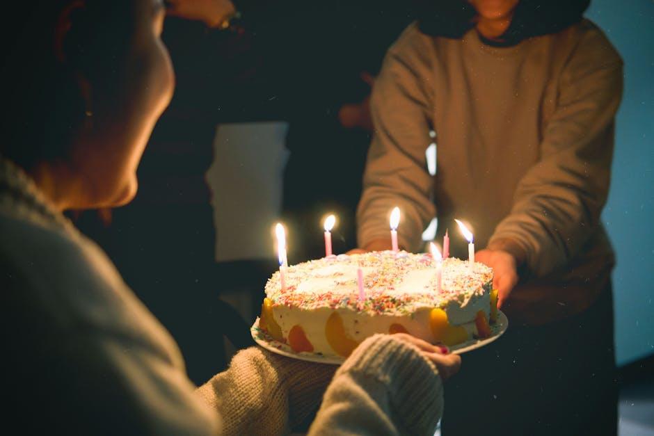 Friends holding a birthday cake with lit candles