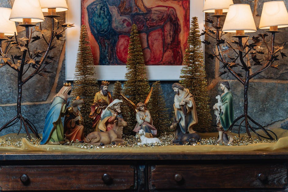 Nativity scene figures on a wooden sideboard with small gold trees