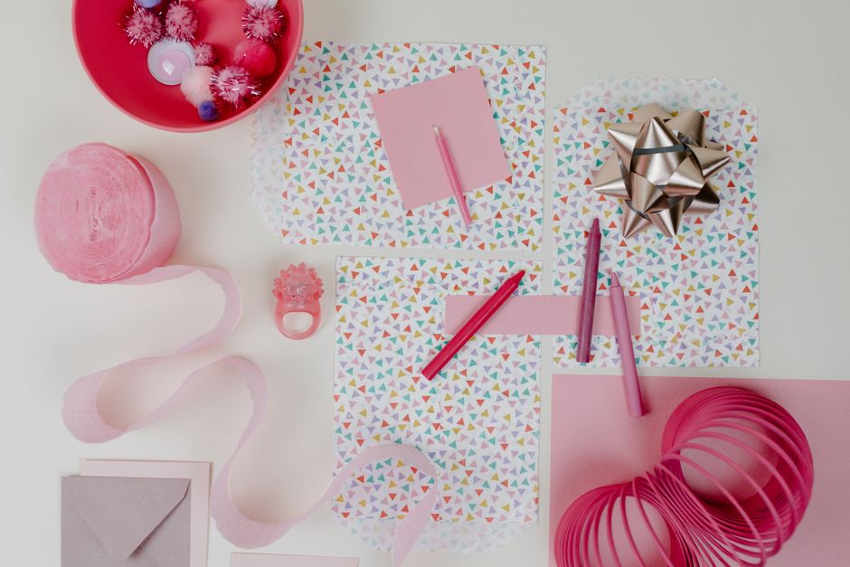 Pink ribbon, party supplies and cards on a table