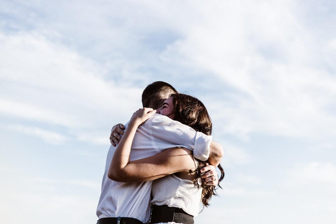 Two people hugging outdoors under a bright sky