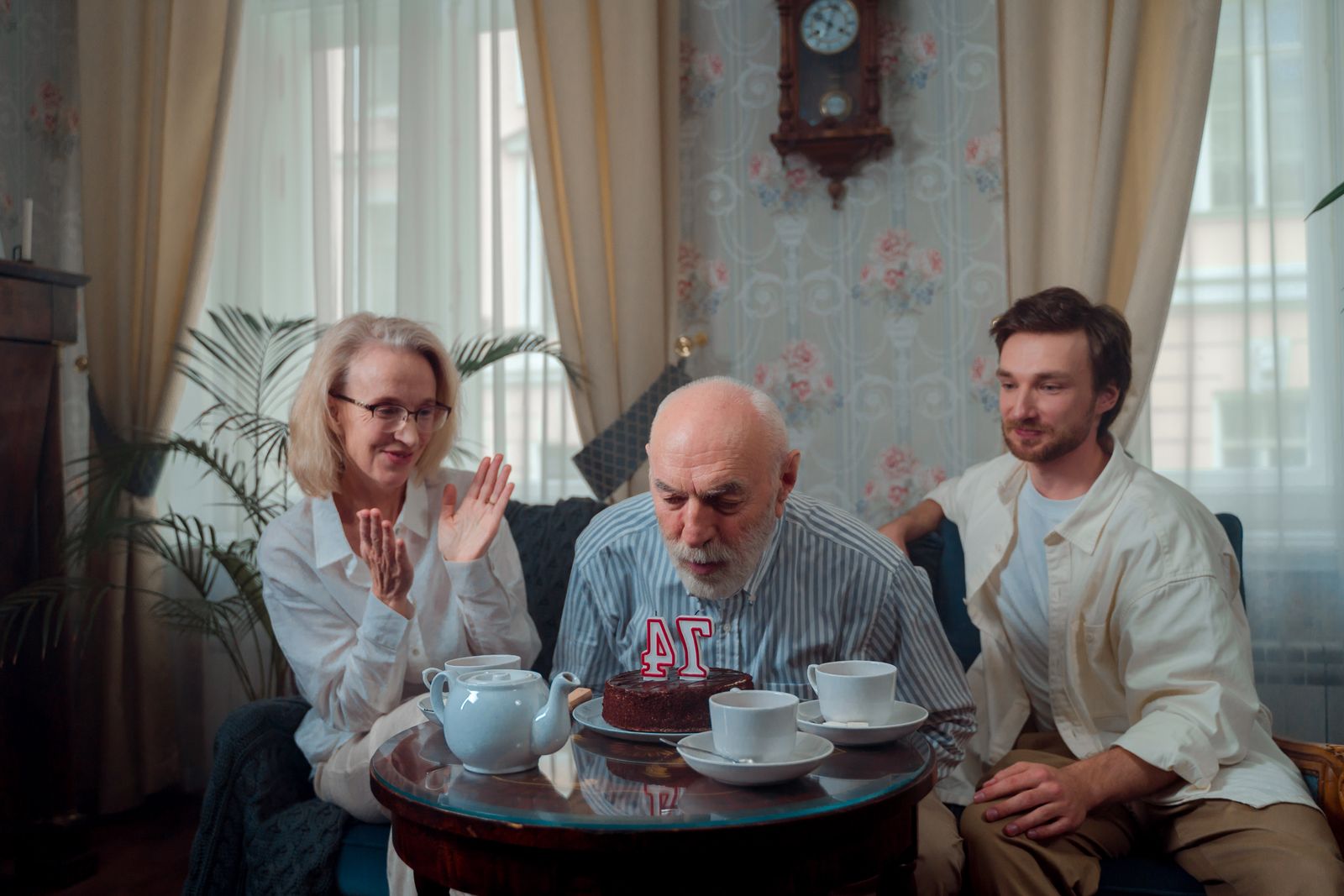 A grandfather blowing out his birthday candles with his family