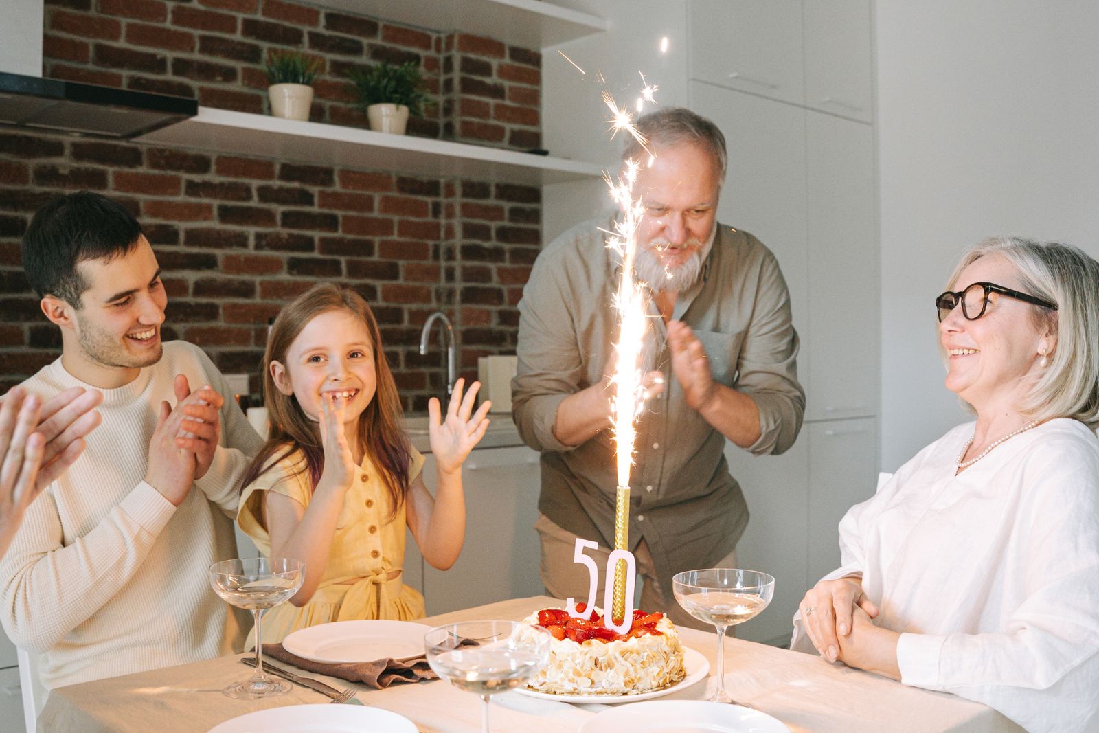 A family celebrating a 50th birthday with a cake and sparkler
