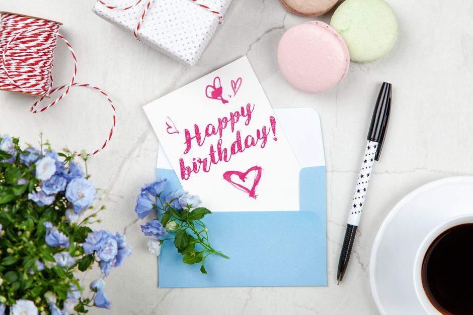 Happy birthday card with flowers, macarons and a pen