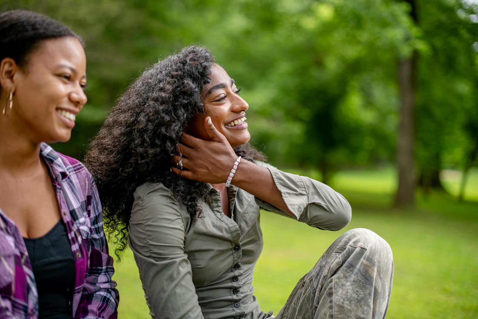 Two smiling women sitting together in a park