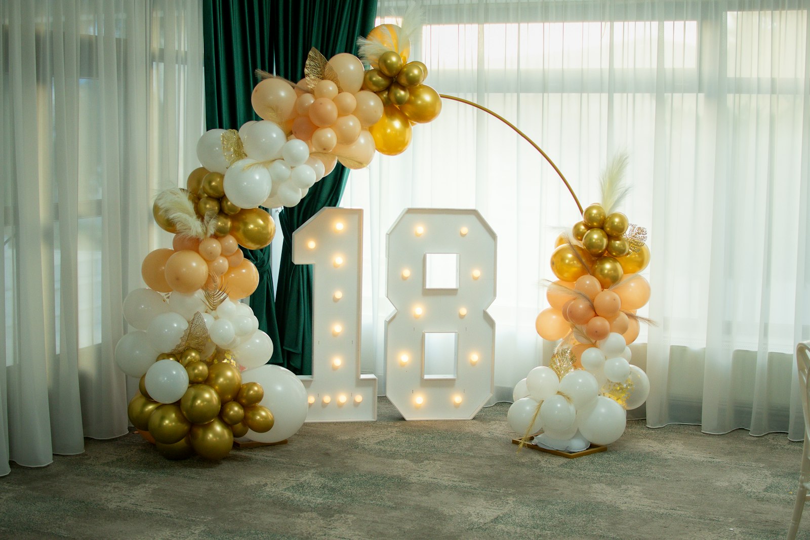 A lit-up number 18 sign with gold and white balloons