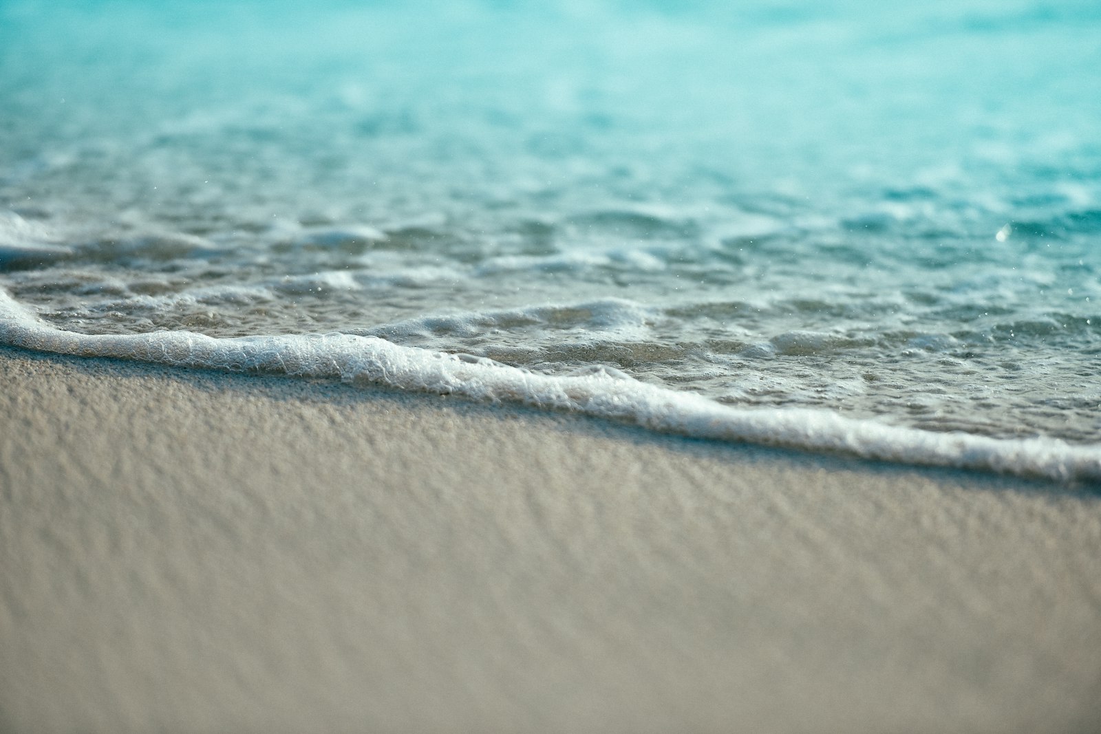 A gentle wave washing over smooth sand on a beach