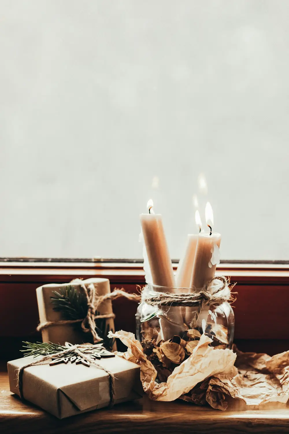 Lit candles on a windowsill next to a small wrapped gift