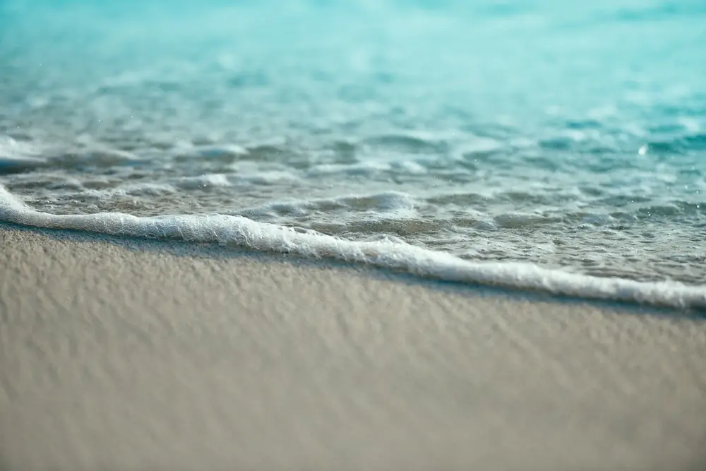A gentle wave washing over smooth sand on a beach