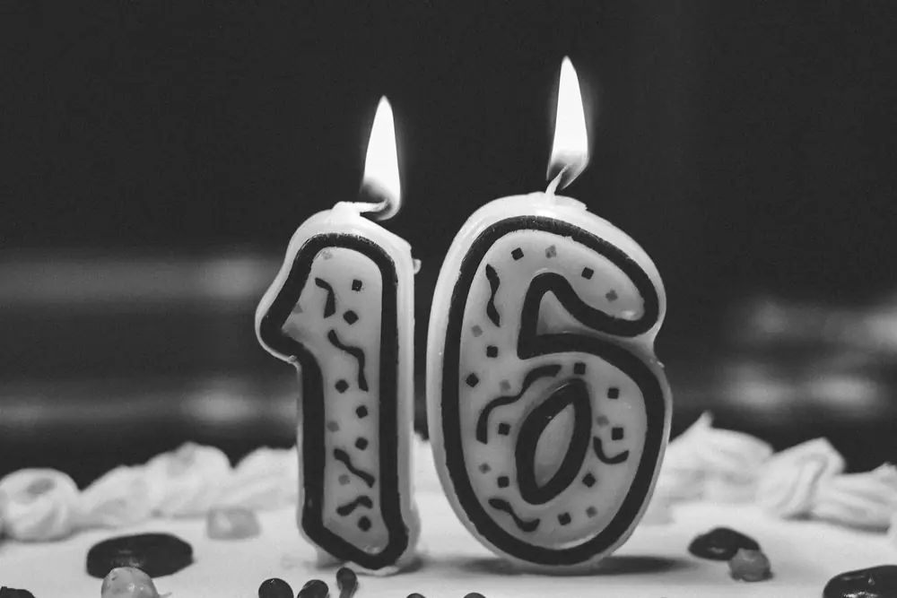 Number 16 birthday candles lit on a frosted cake