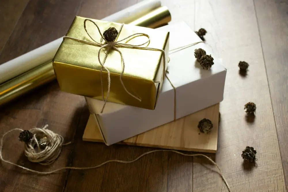 Two wrapped gifts tied with twine on a wooden table