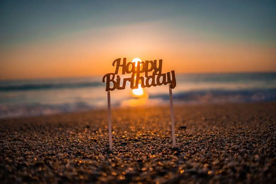A Happy Birthday cake topper on the beach at sunset