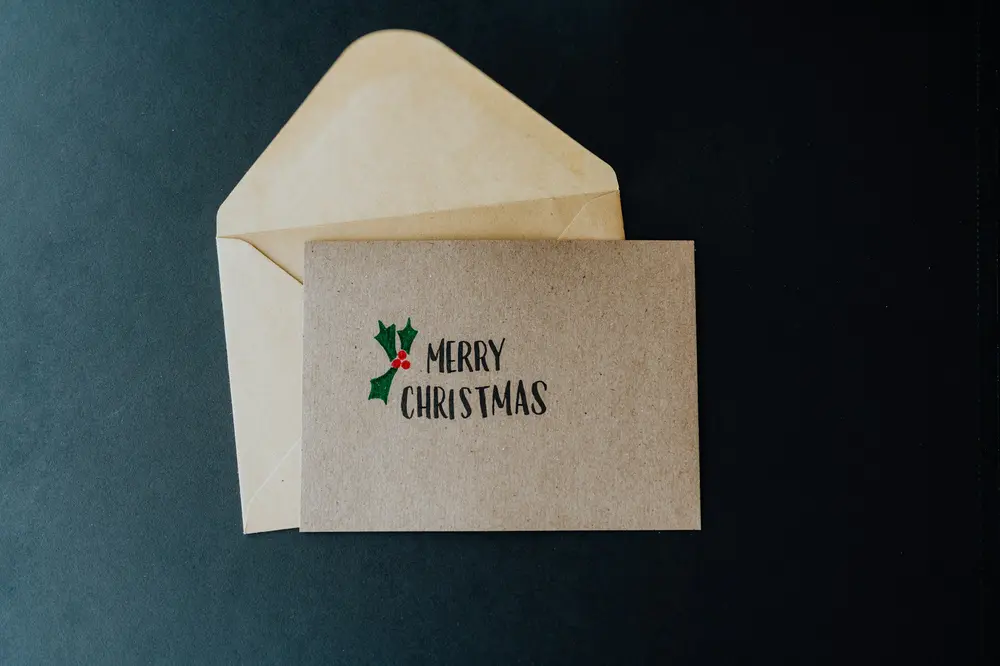 A Merry Christmas card and kraft envelope on a dark blue background