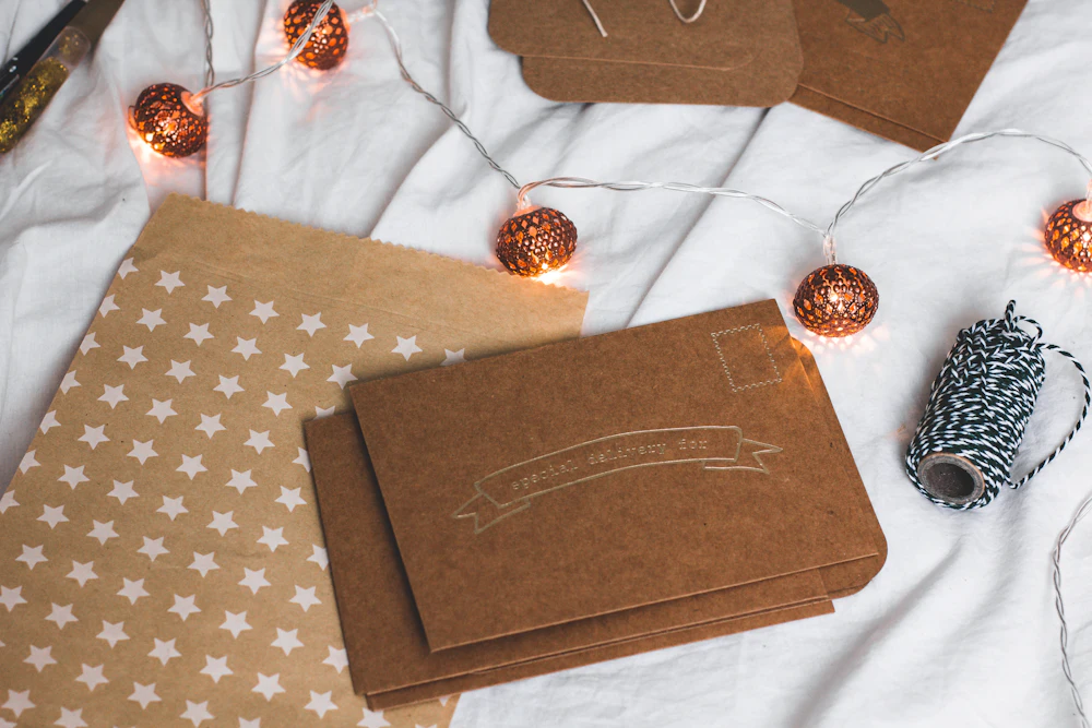 Kraft paper envelopes and cards with string lights on a white blanket