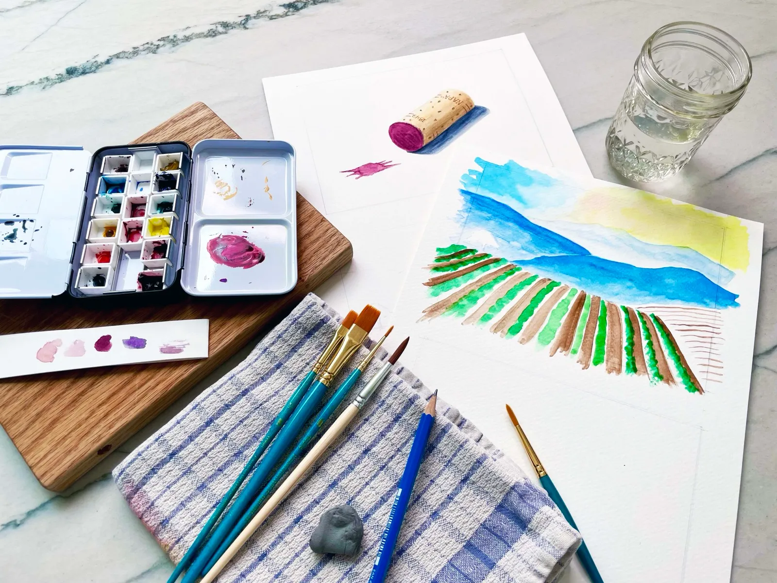 Watercolor class setup with palette, brushes, and paper.