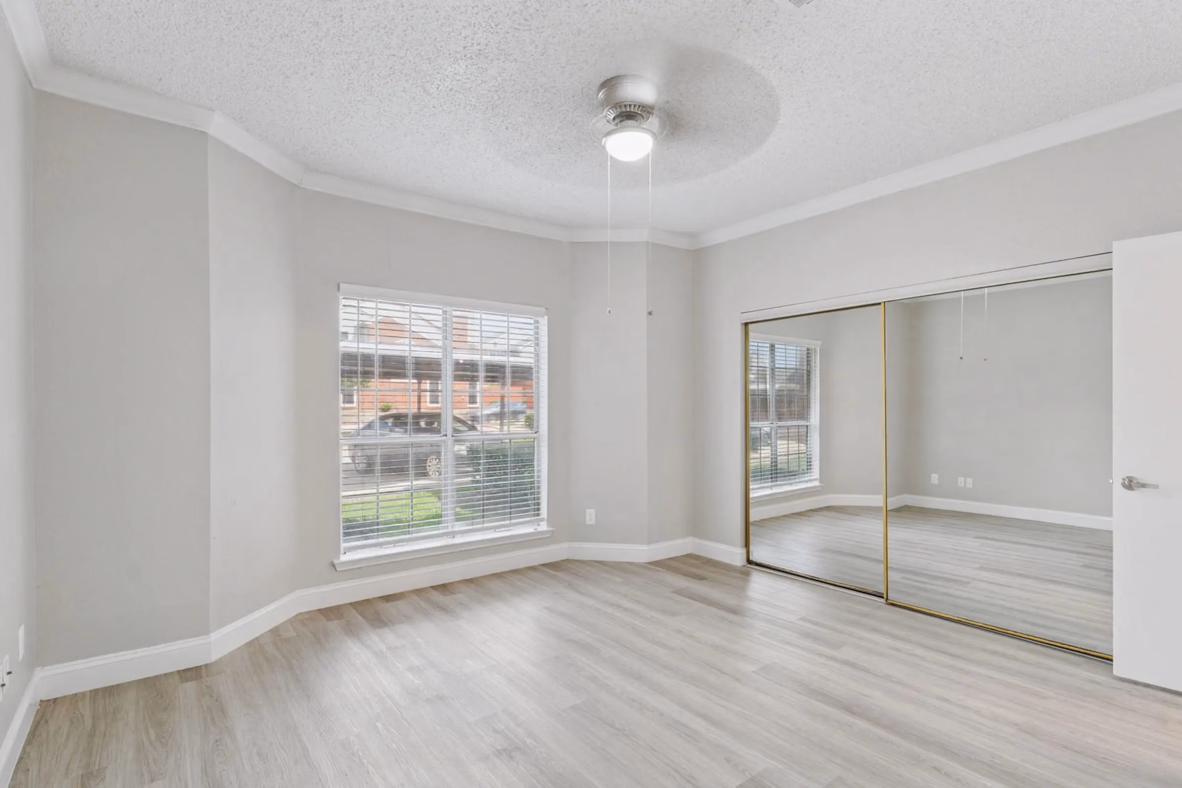 Bedroom with large window and glass mirror closet at Willow Ridge Townhomes and Apartmnets in Euless, Texas