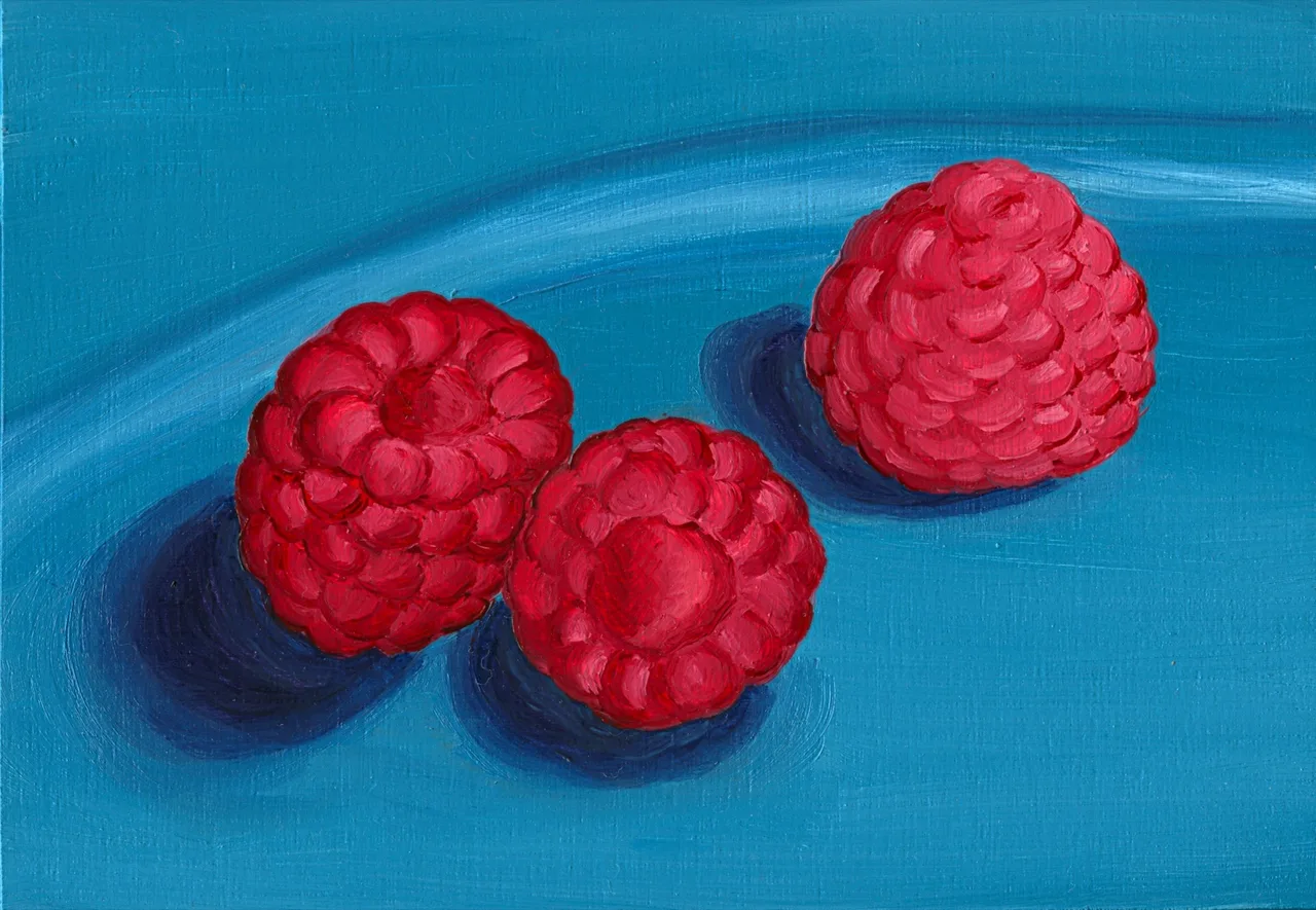 Three red raspberries casting shadows on a blue surface in a close-up view.