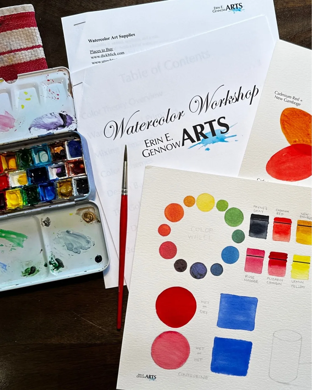 Workshop materials: a watercolor pan set, a brush, and a color wheel practice sheet with painted circles and squares.