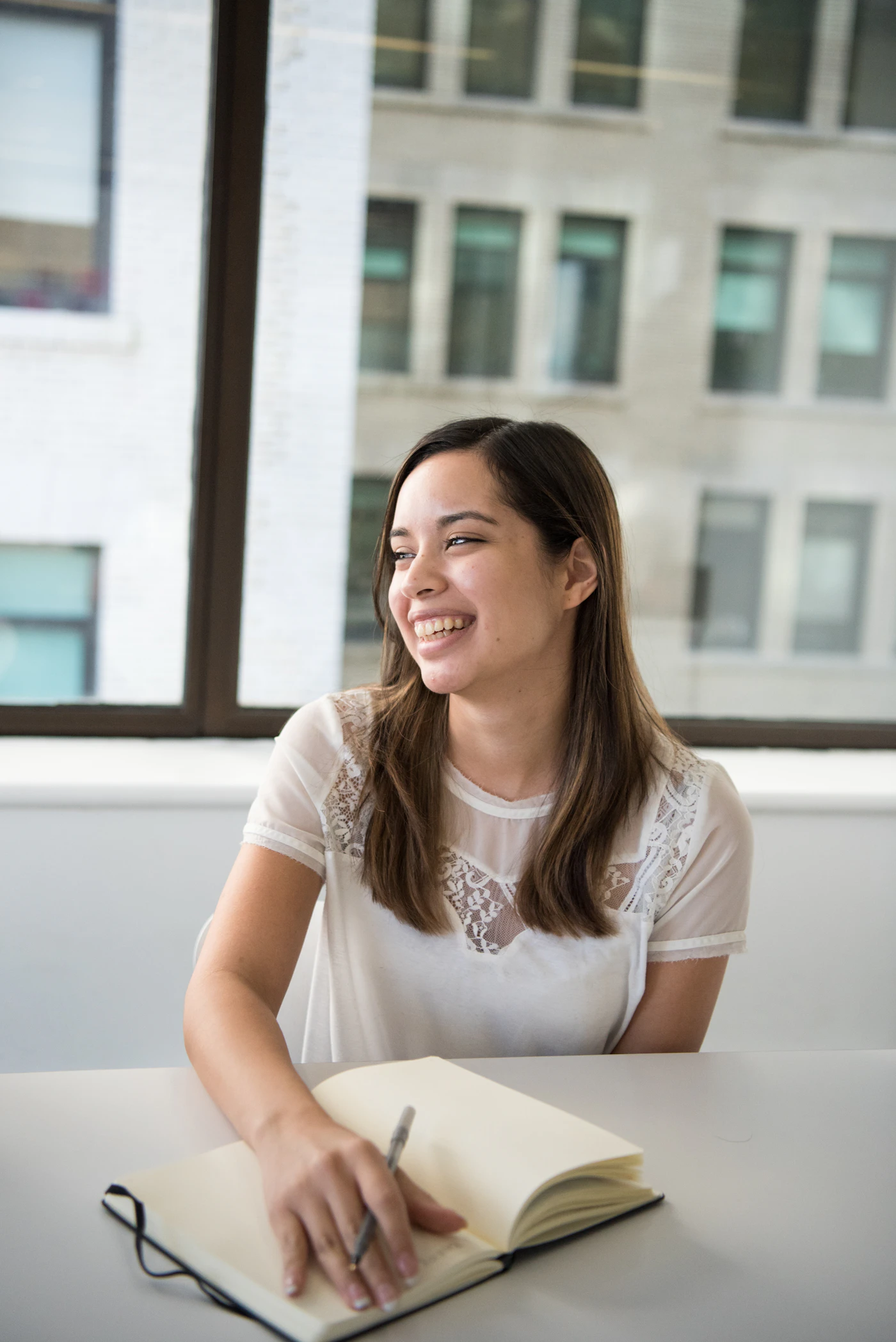 Smiling woman studying at a table with an open notebook