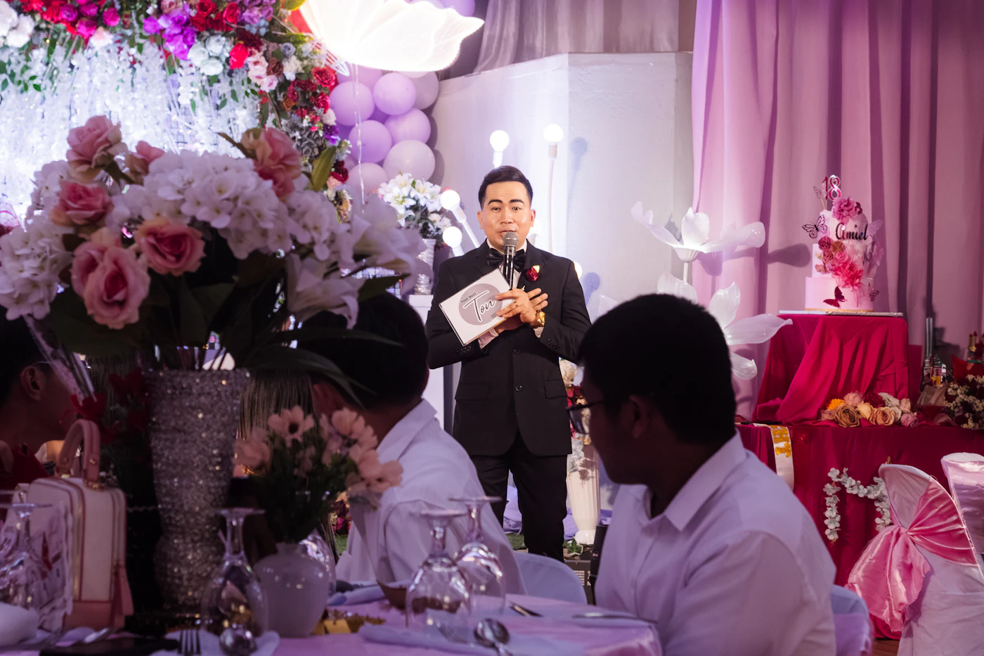 Wedding emcee speaking to guests at a decorated reception
