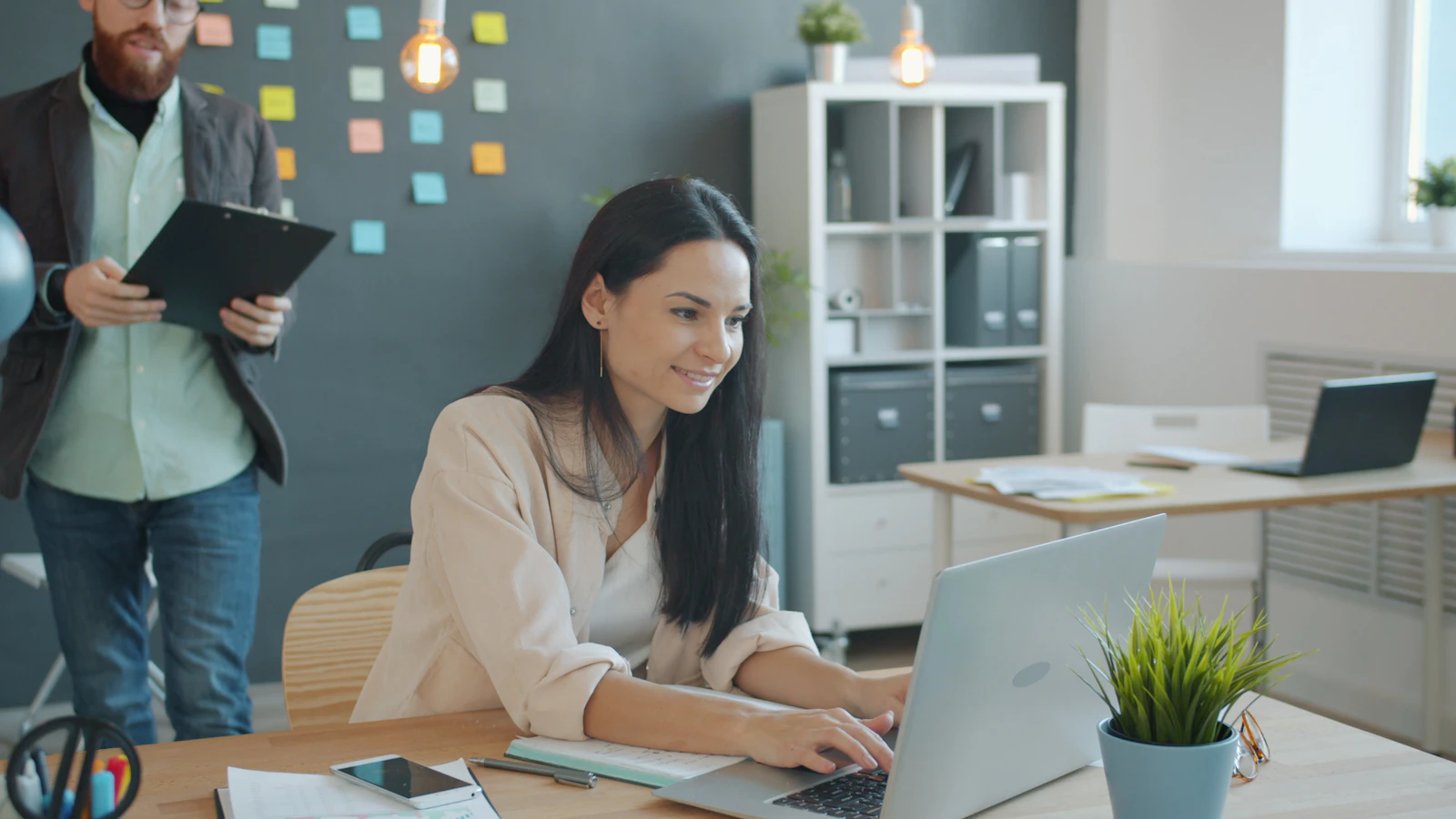 Event planner working at a laptop while a colleague reviews a clipboard