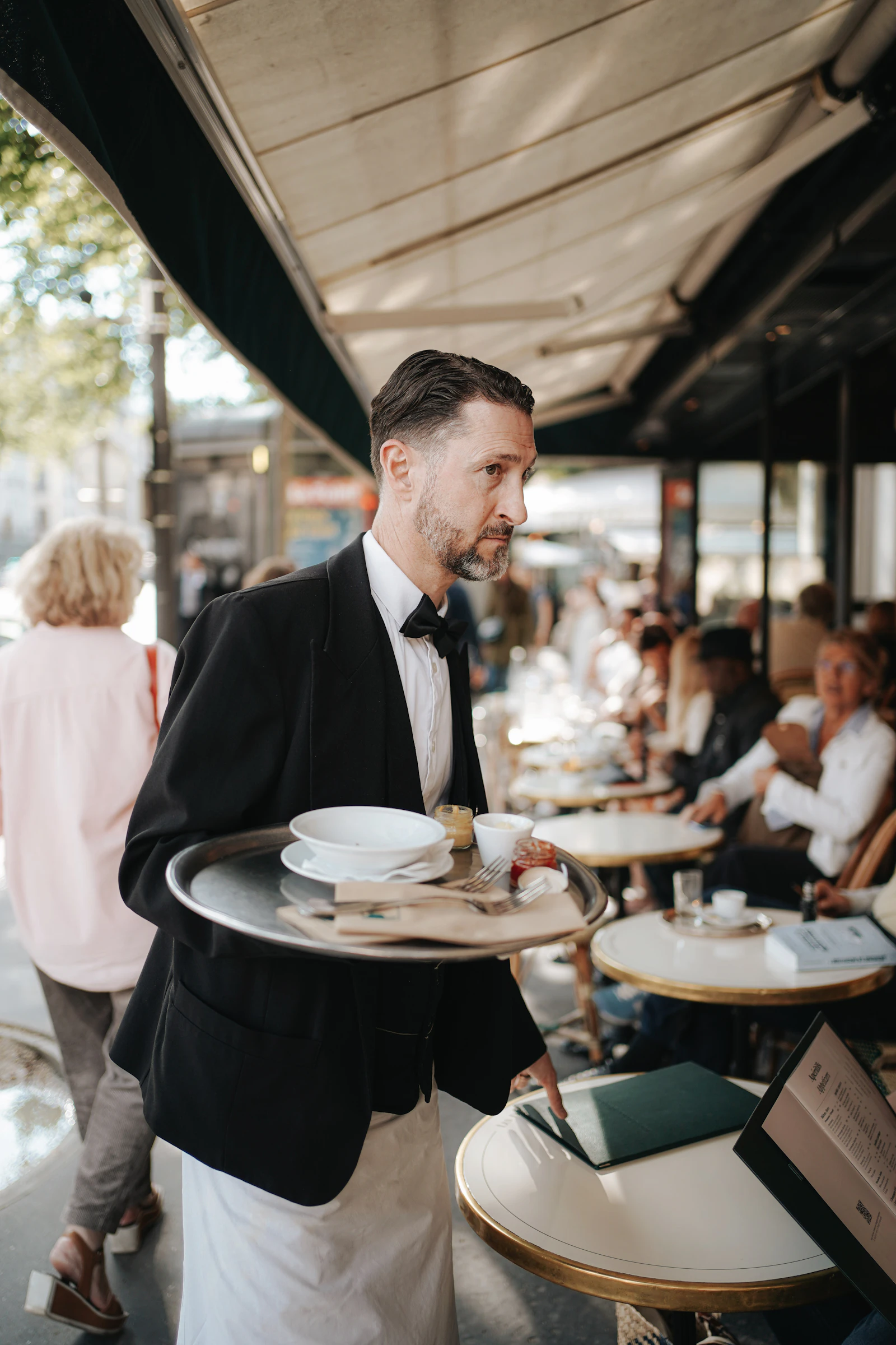 Server carrying a tray through a busy dining patio
