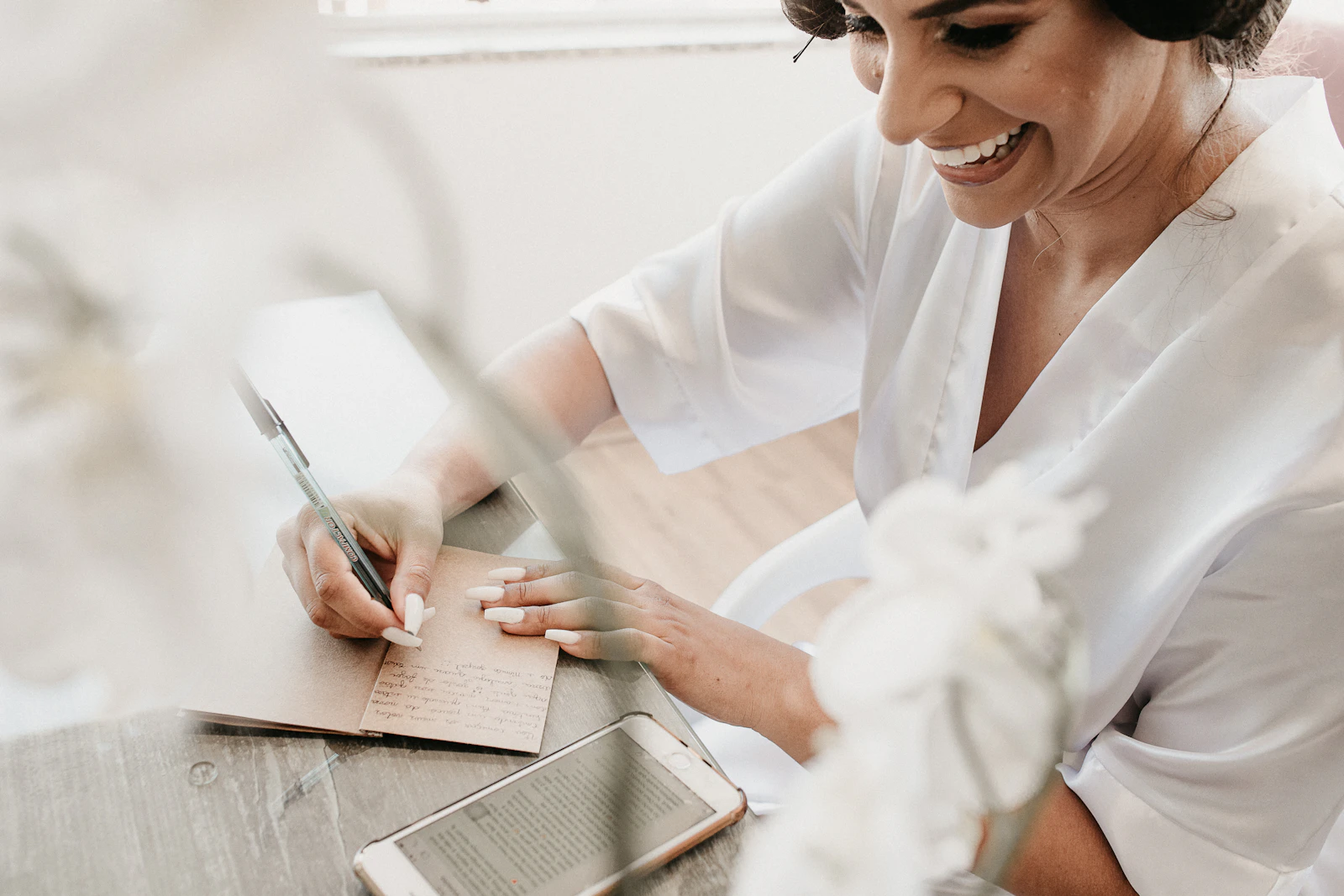 Smiling bride writing notes while getting ready on her wedding day