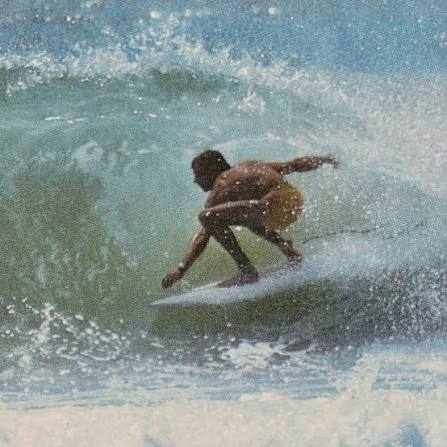 Vintage photo of a surfer crouched low through a breaking wave