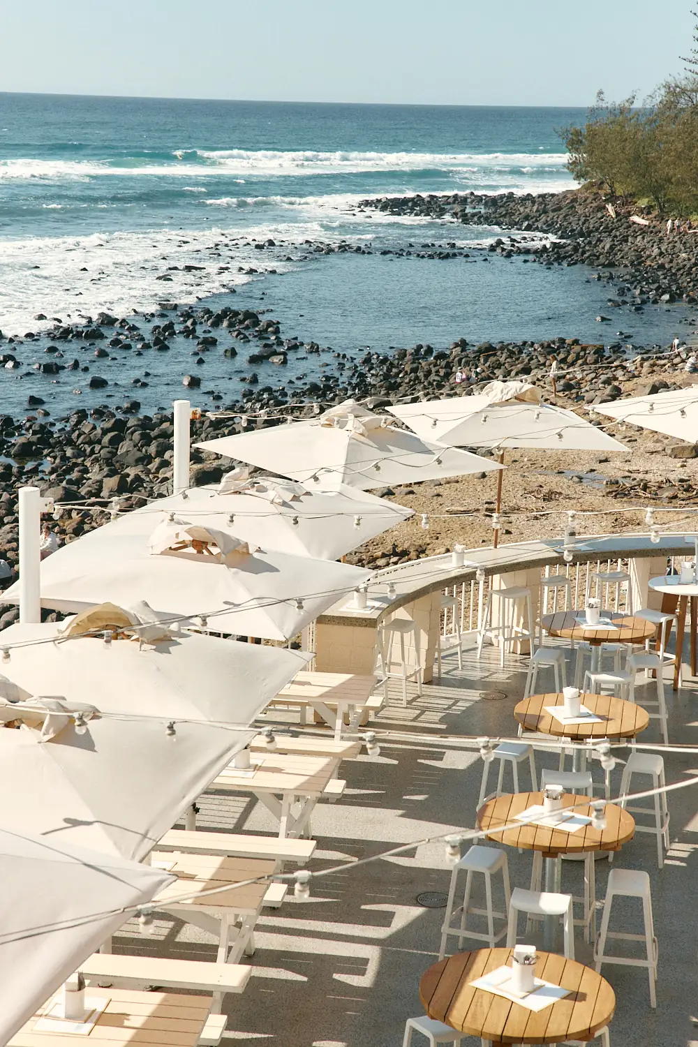 Umbrella-shaded deck seating above the rocks and surf at Burleigh Heads