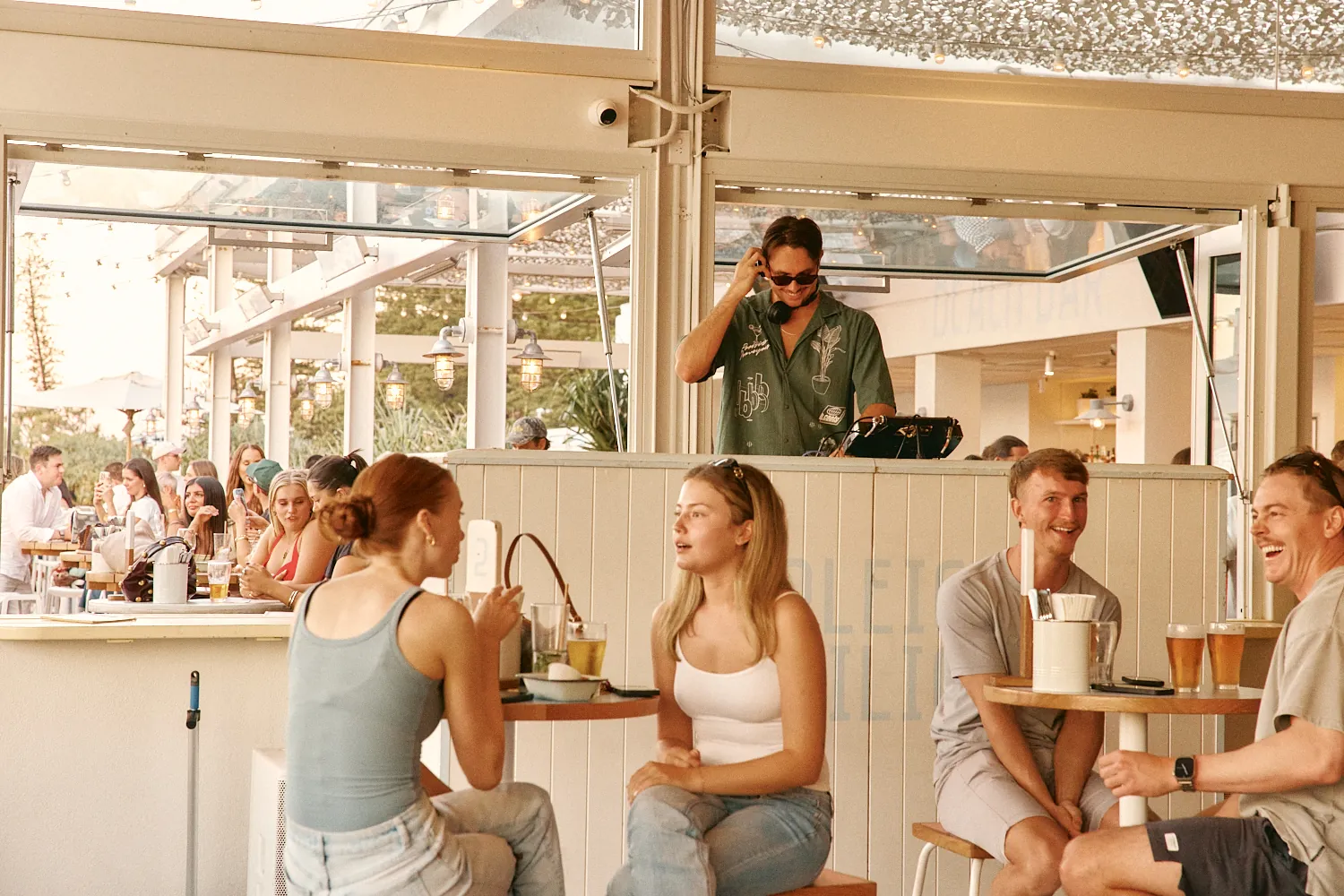 Guests laughing over drinks as a DJ plays behind the bar