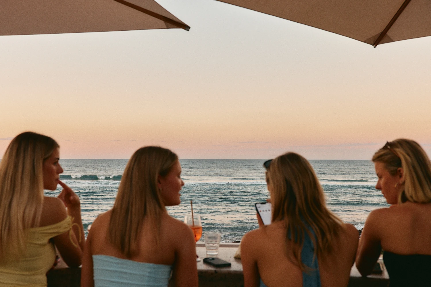 Friends with drinks watching the ocean at sunset from the terrace bar