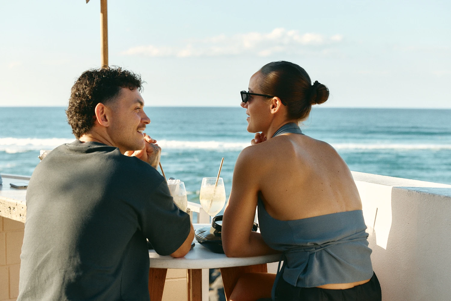 Couple sharing drinks at a table overlooking the ocean