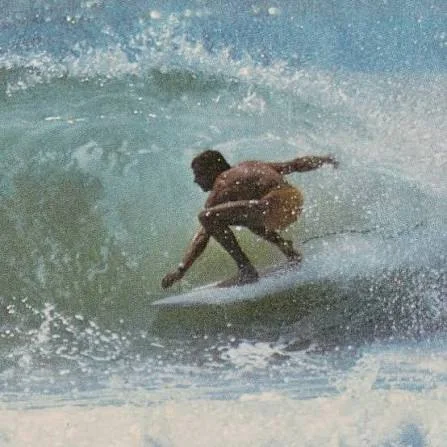 Vintage photo of a surfer crouched low through a breaking wave