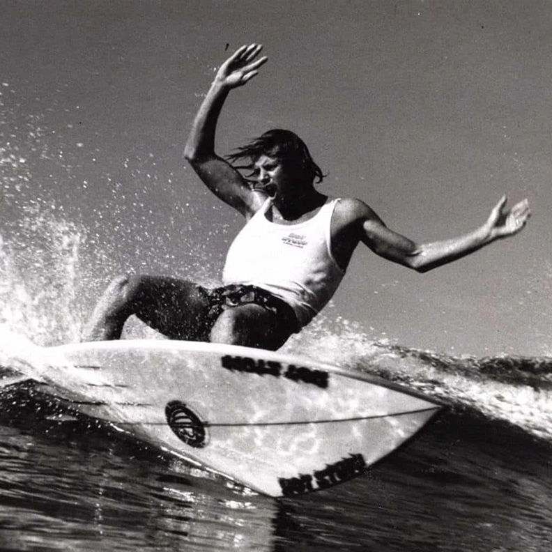 Black and white photo of a surfer riding a wave with arms outstretched