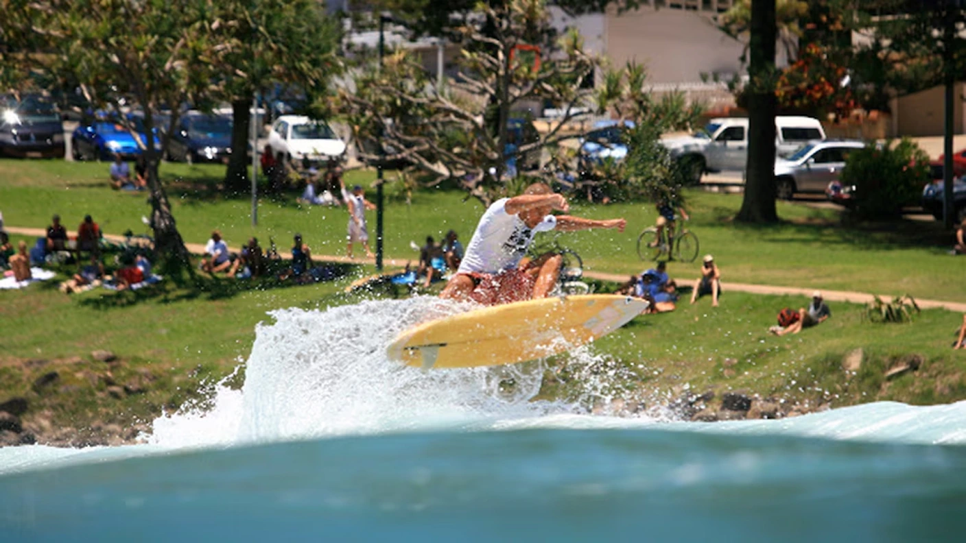 Surfer launching off a wave in front of spectators in the park at Burleigh Heads