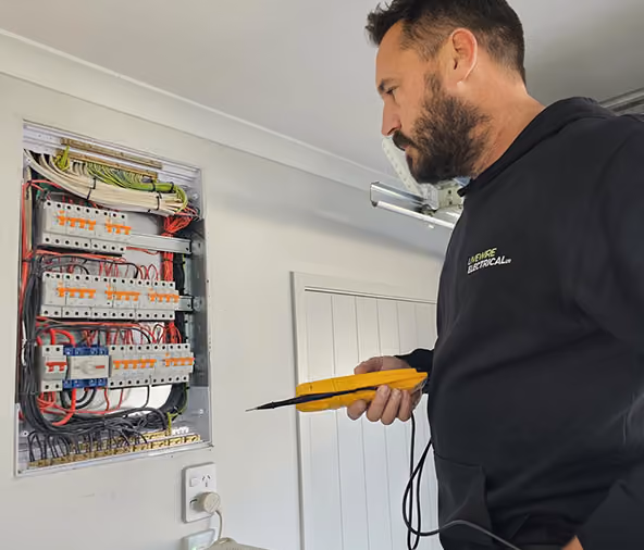 Livewire electrician testing a residential switchboard with a multimeter