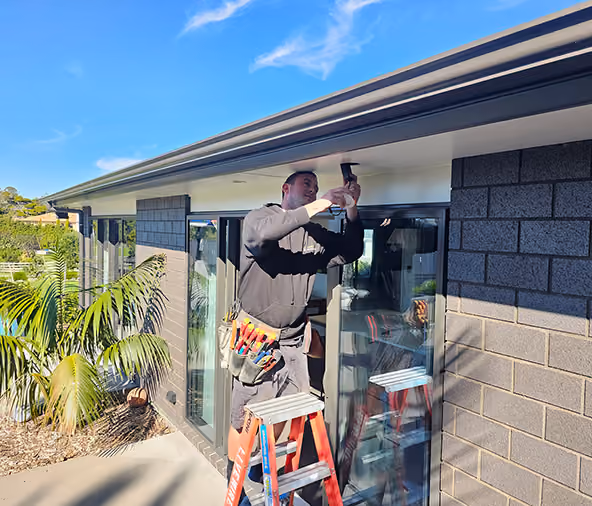 Livewire electrician fitting an exterior light to a new Auckland home